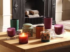 a series of colored candles on a coffee table in front of a fireplace