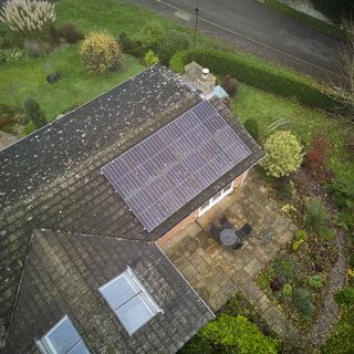 Overhead view of house with solar panels on roof surrounded by garden
