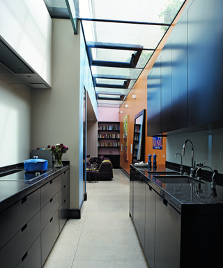 A modern kitchen with large sky lights, black cabinetry and pops of color.