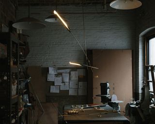 'Two arm pendant' hangs above a workbench. Ball and socket fixtures are on the bench.