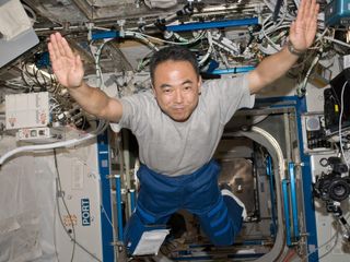 astronaut with hands outstretched floating in space station