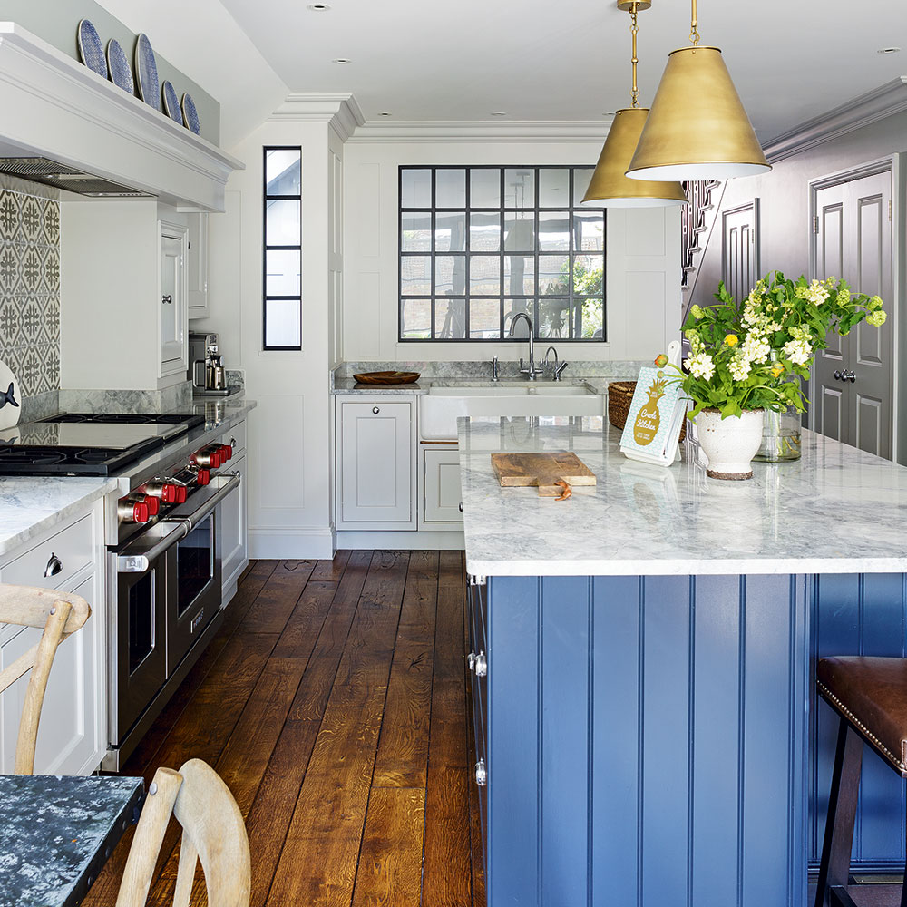 kitchen with white walls wooden flooring and white marble countertop with potted plants