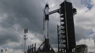 dark clouds in the sky above a white rocket upright on a launch pad