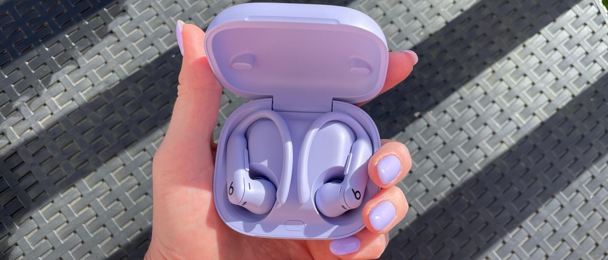 Powerbeats Pro 2 held in a woman&#039;s hand with perfectly-matching purple nail polish