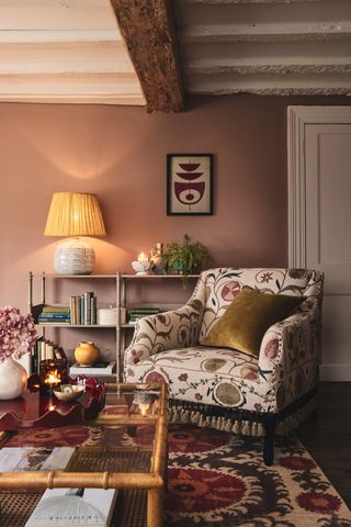 Living room with dusky pink walls, armchair, table lamp and candles