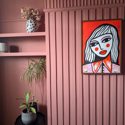 Terracotta room with houseplants and bright painting of abstract woman on wall