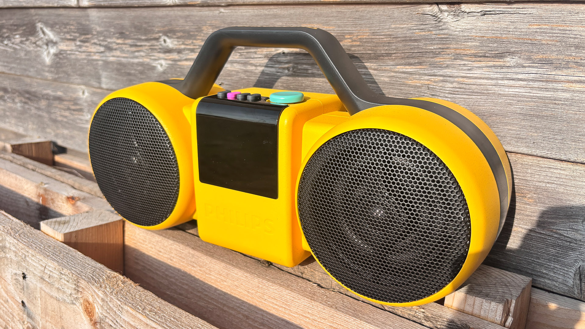 Philips The Roller wireless speaker on wood pallet in front of fence