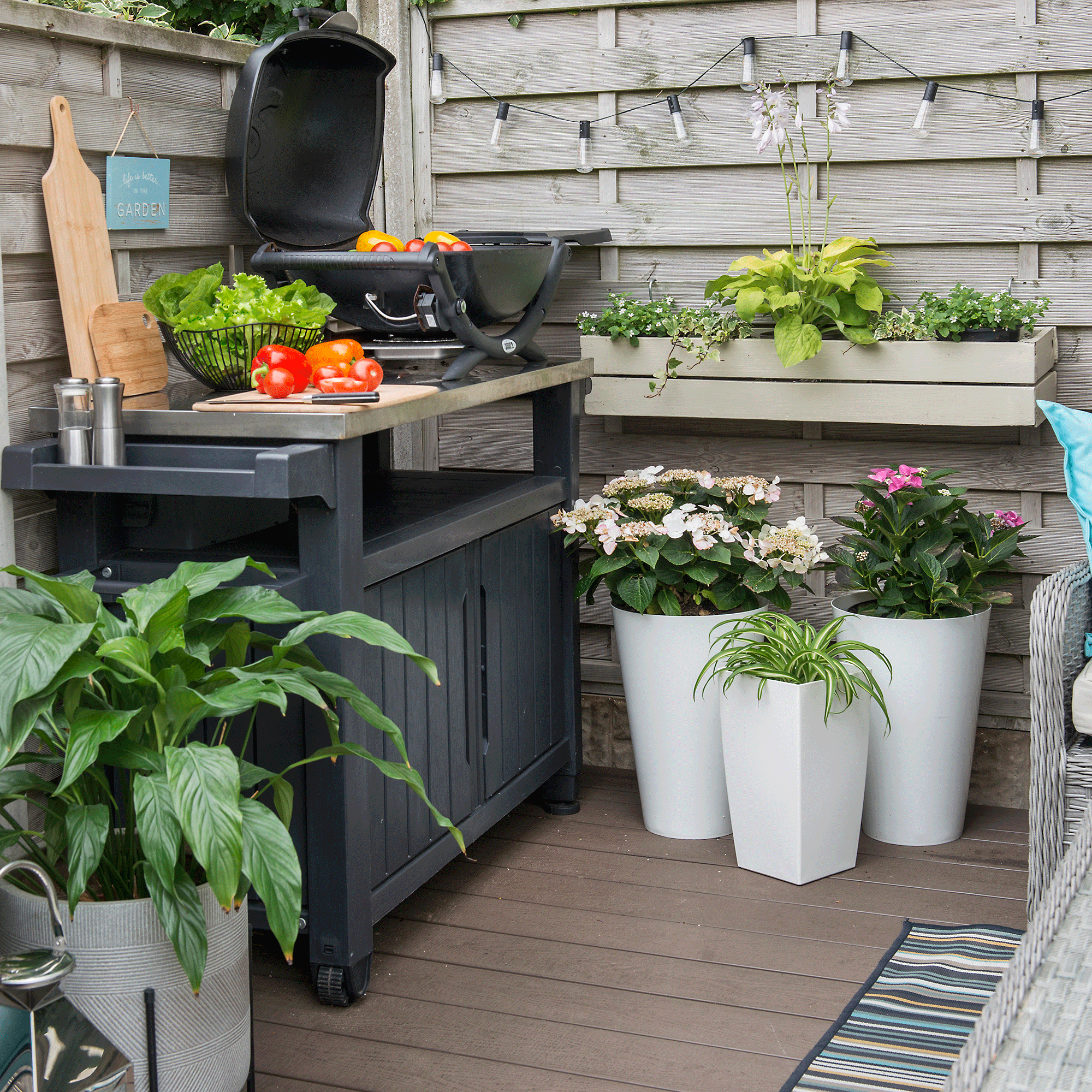 BBQ in outdoor kitchen with decking and large white planters
