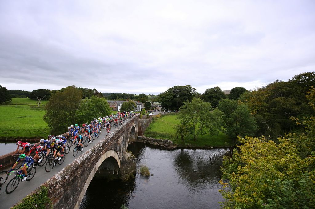 The peloton passes over a bridge in the bucolic surrounds of Cumbria