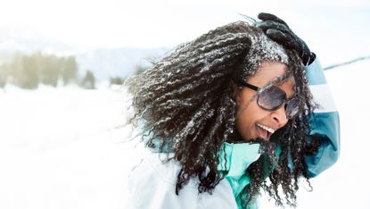 Woman is smiling outdoors as snow is falling