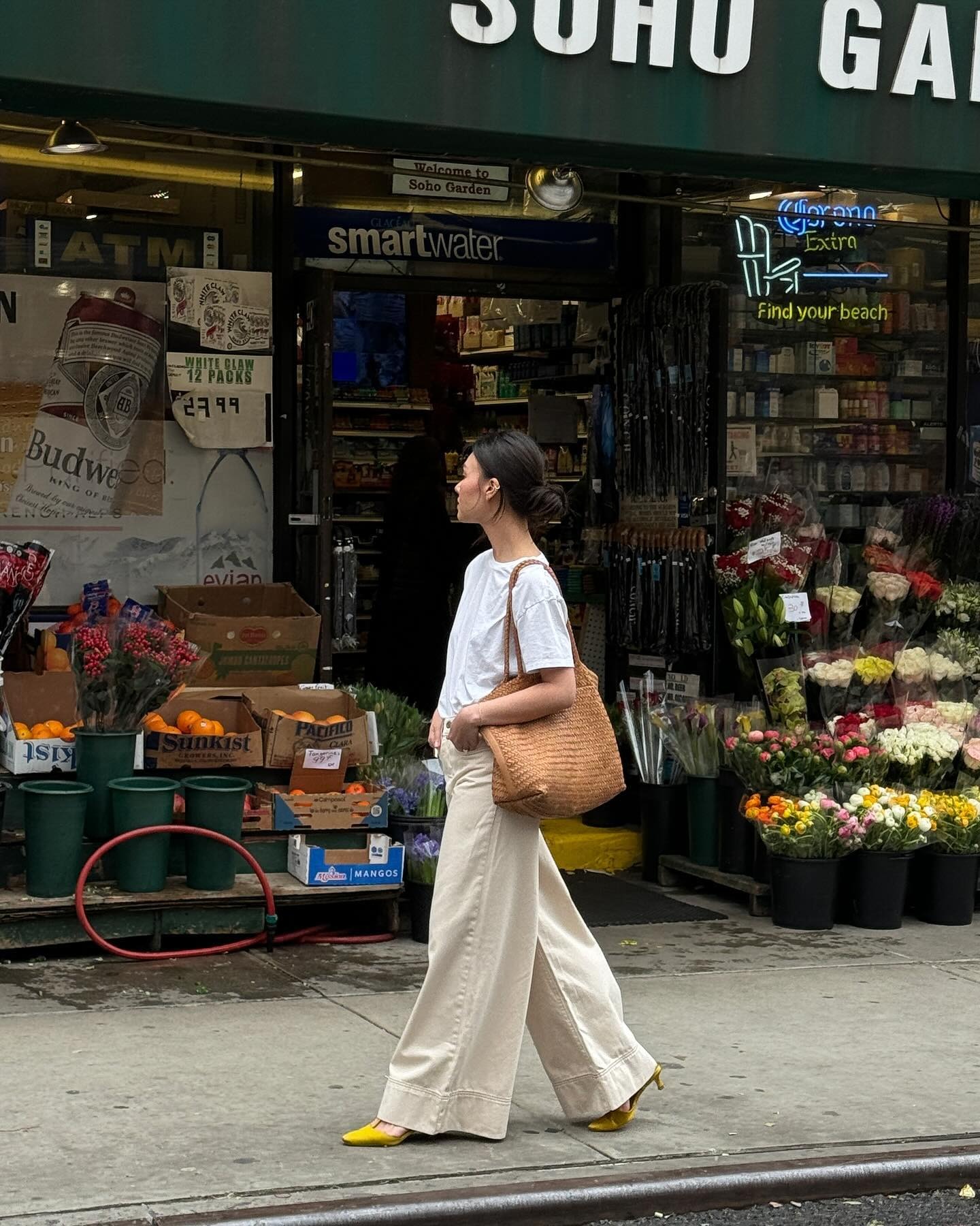 Influencer @mimixn wears a white t-shirt with beige jeans, yellow sandals and a light brown woven bag.