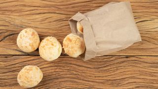 Round rolls cascading out of a brown paper bag on a worktop