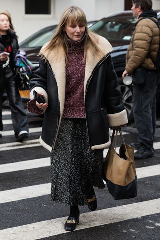 A woman at fashion week with a shearling coat and skirt