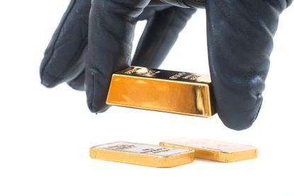Gloved hand reaching for gold bar