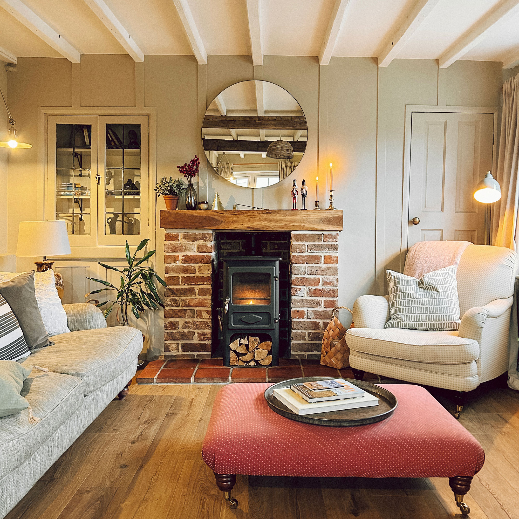 Living room with round mirror above brick-sided fireplace