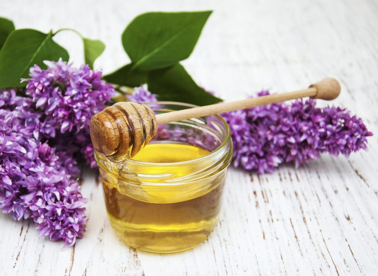 Jar Of Honey Next To Purple Flowers