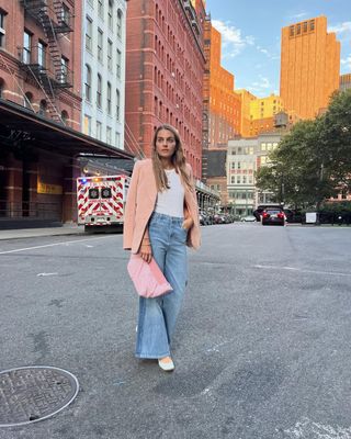 Vee Collective co-founder Lili Radu wearing a pink blazer, jeans, flats, and a pink Vee Collective Caba Clutch in NYC