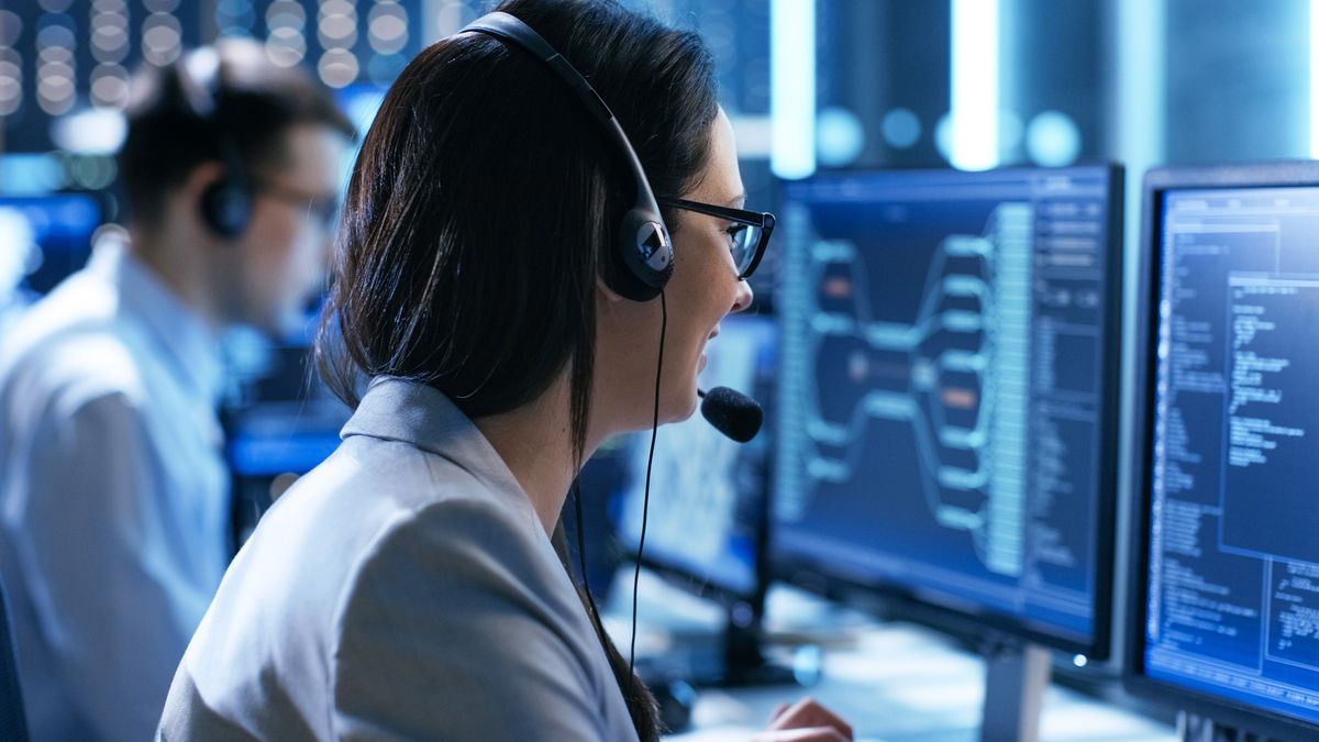 A woman wearing a headset looking at a computer screen