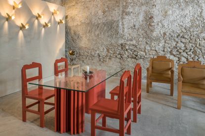 tables and chairs by Alekos Fassianos in front of bare stone walls