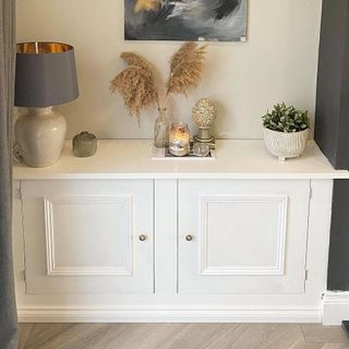 white cupboard with blue lamp and wall painting