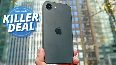iPhone 16e held in the hand with killer deal badge nearby.