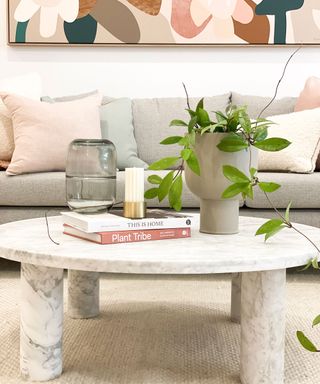 Round marble coffee table styled with trailing houseplant, glass vessel, books and candle
