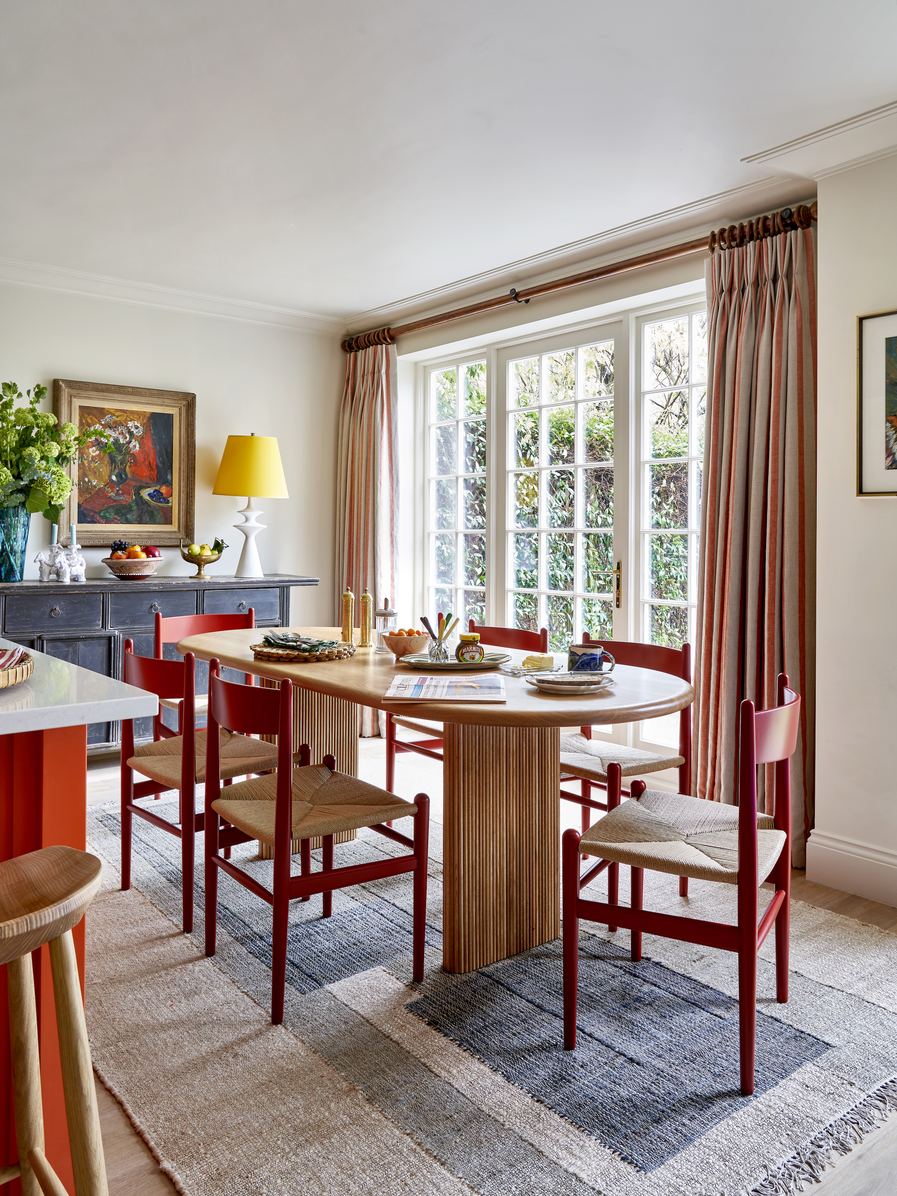 Colorful dining area with red chairs and wooden oval table