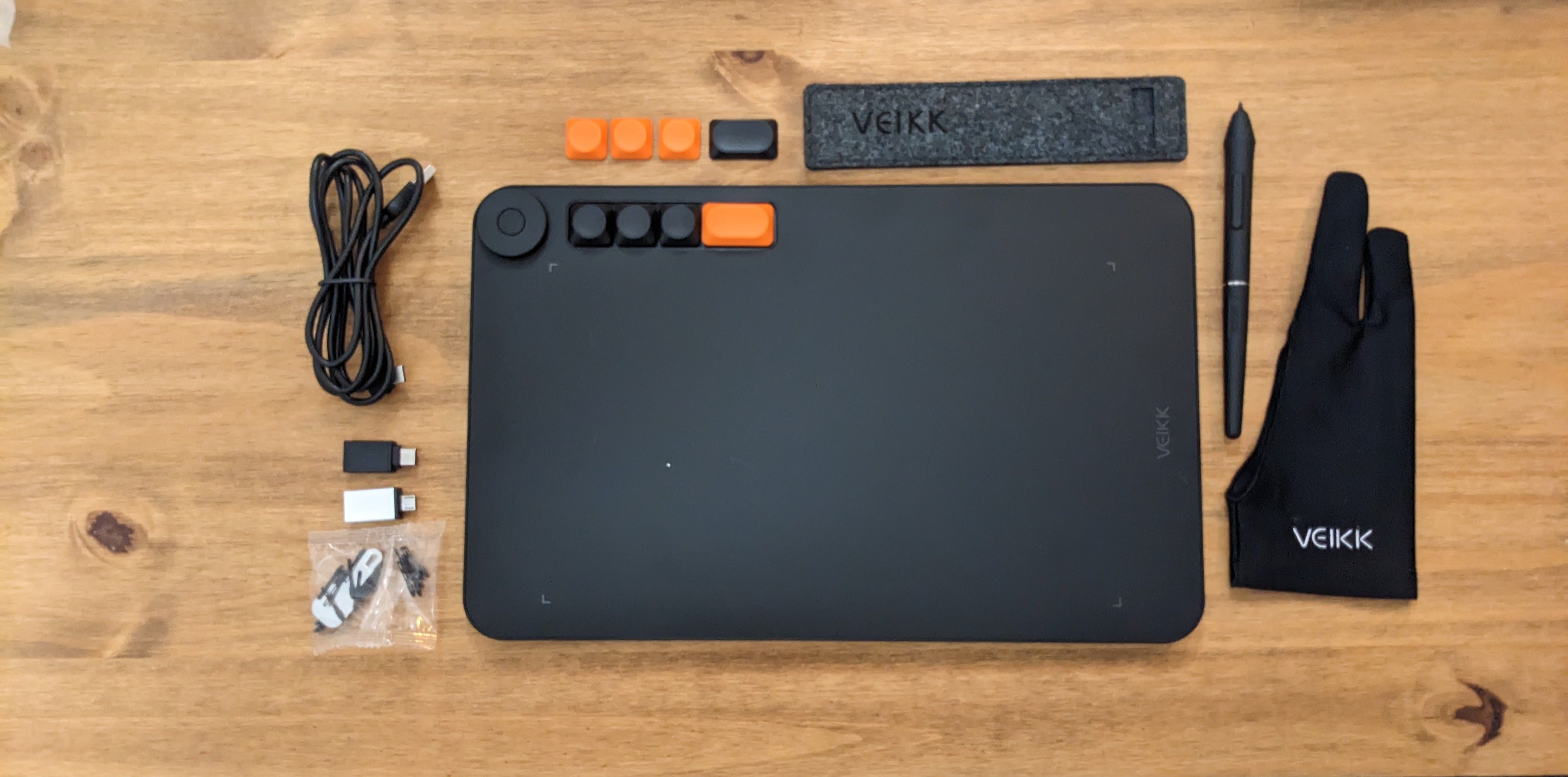 A black Veikk Voila L Pen Tablet sitting on a wooden desk