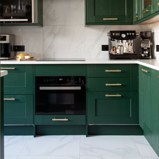 green and white kitchen with marble splash back and matching floor tiles, brass handles