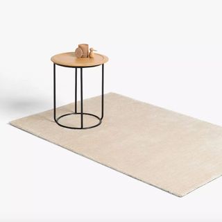 John Lewis & Partners Plain Easy Care Rug in ivory colour on the floor with metal and wood side table on top