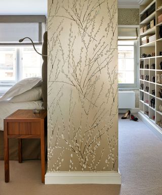 Walk-in wardrobe ideas divided from the main bedroom by a wall with gold leaf wallpaper, with a wall of shoe storage.