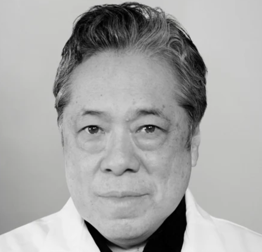 a black and white photo of an older asian man in a white lab coat