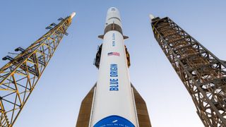 A white and blue Blue Origin rocket stands atop its launch pad for a NASA Mars launch.