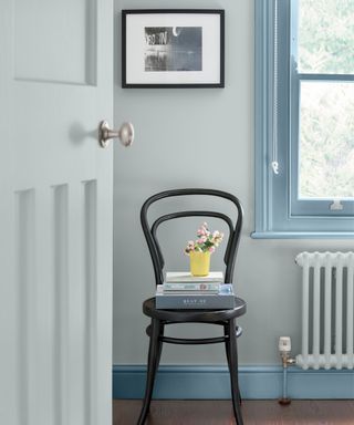 blue hallway with black dining chair and darker blue painted skirting boards and window frame