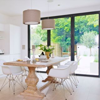 Closed bifold doors with black frames off neutral coloured dining area, offering views of the garden