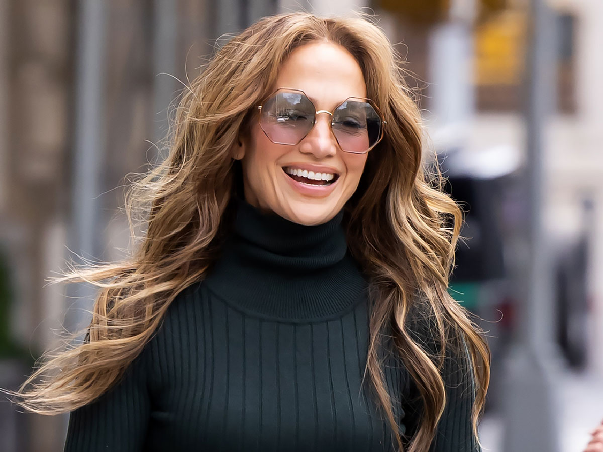 Jennifer Lopez looking away from the camera and smiling wearing large sunglasses