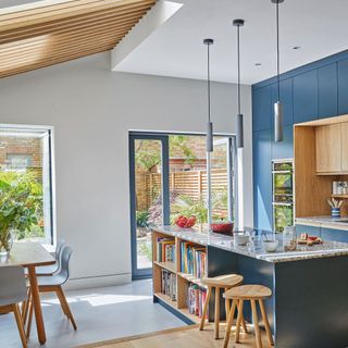 kitchen diner with wooden rafters in ceiling and blue and stone island unit