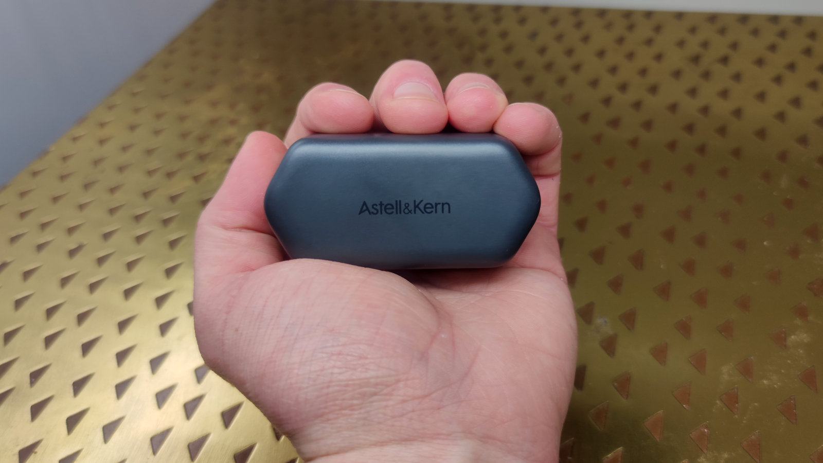 The Astell & Kern AK UW100MKII's charging case held in the palm of a hand.
