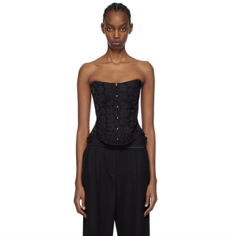 a model wears a stella mccartney corset top while standing in front of a plain backdrop