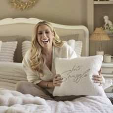 Stacey Solomon on bed holding cushion.