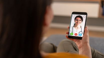 A person holding a phone during a telehealth meeting