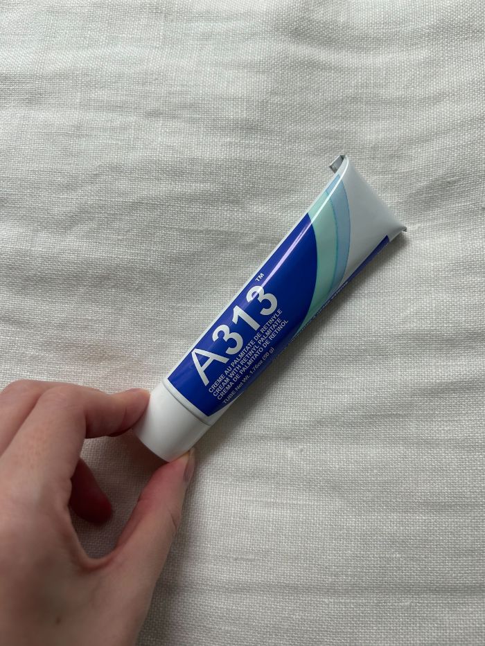 Junior beauty editor Grace Lindsay holding the A313 retinol on a white linen background