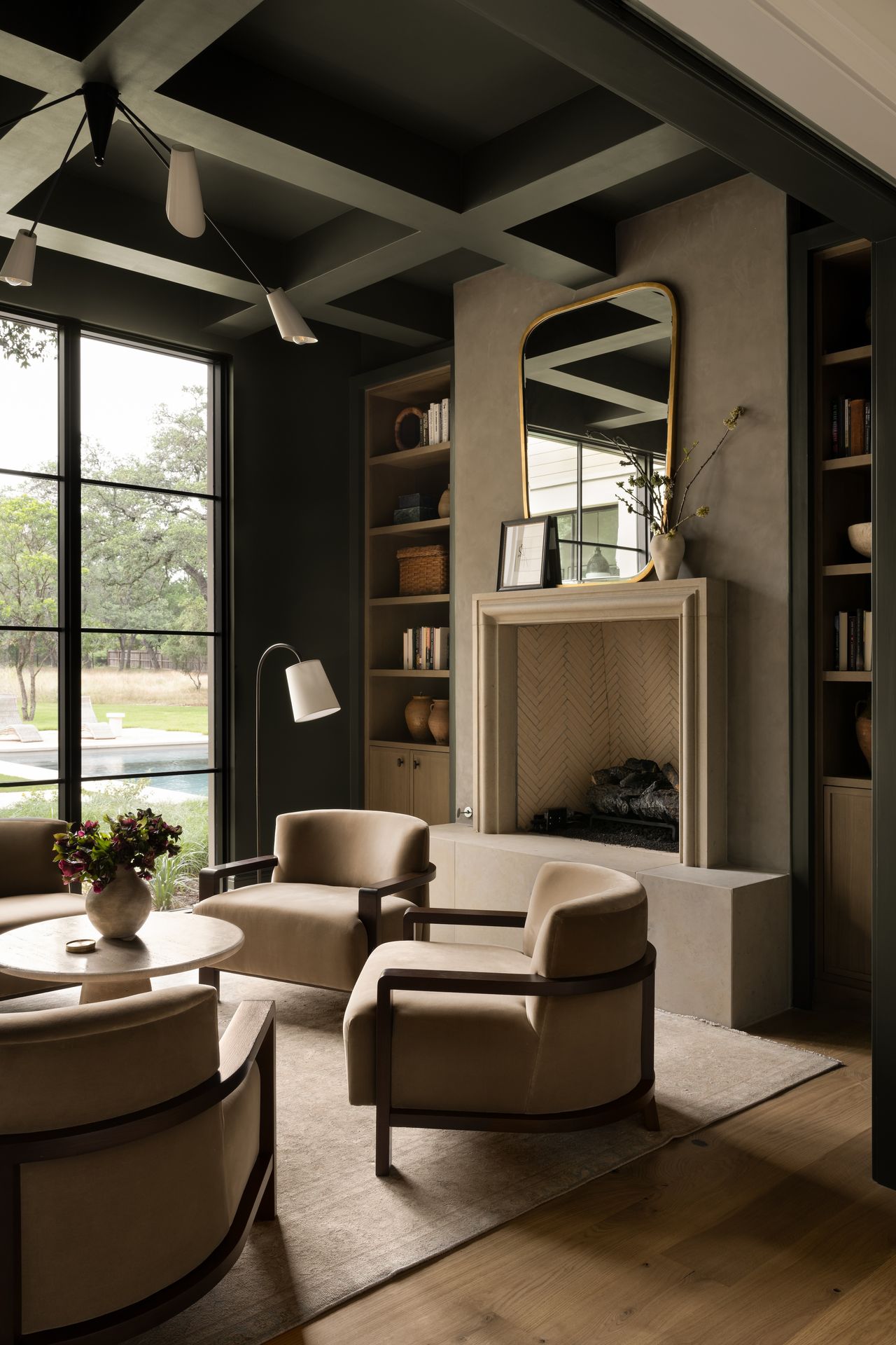 A clutch of club chairs surround a simple coffee table in a seating area alongside a fireplace.