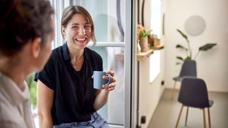 Woman smiling and drinking coffee, an example of what not to drink if you want to whiten teeth naturally