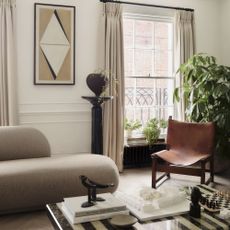 neutral living room with curved sofa, striped marble coffee table and cream curtains