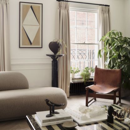 neutral living room with curved sofa, striped marble coffee table and cream curtains