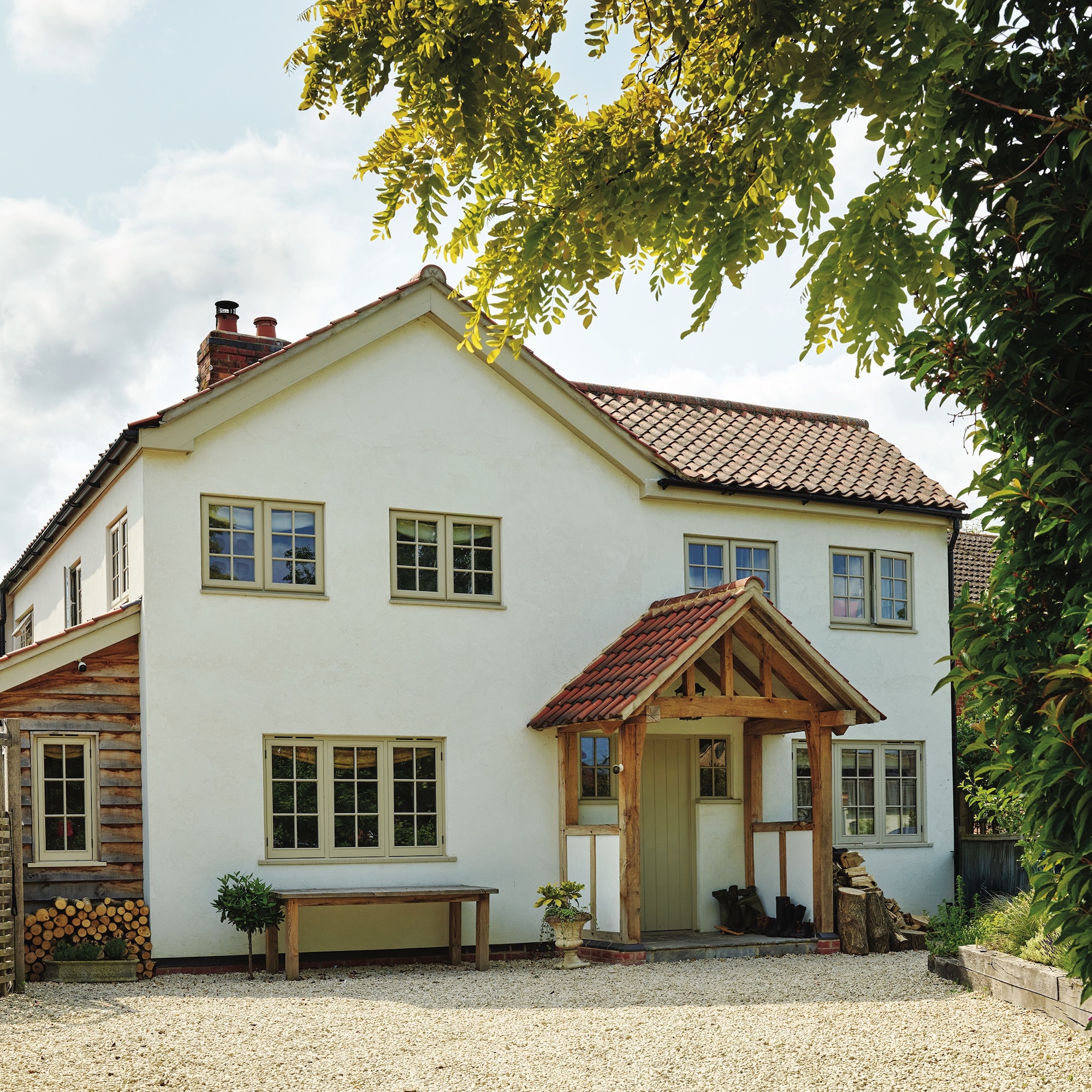 exterior of extended white painted rendered cottage with pitched roof and timber frame porch