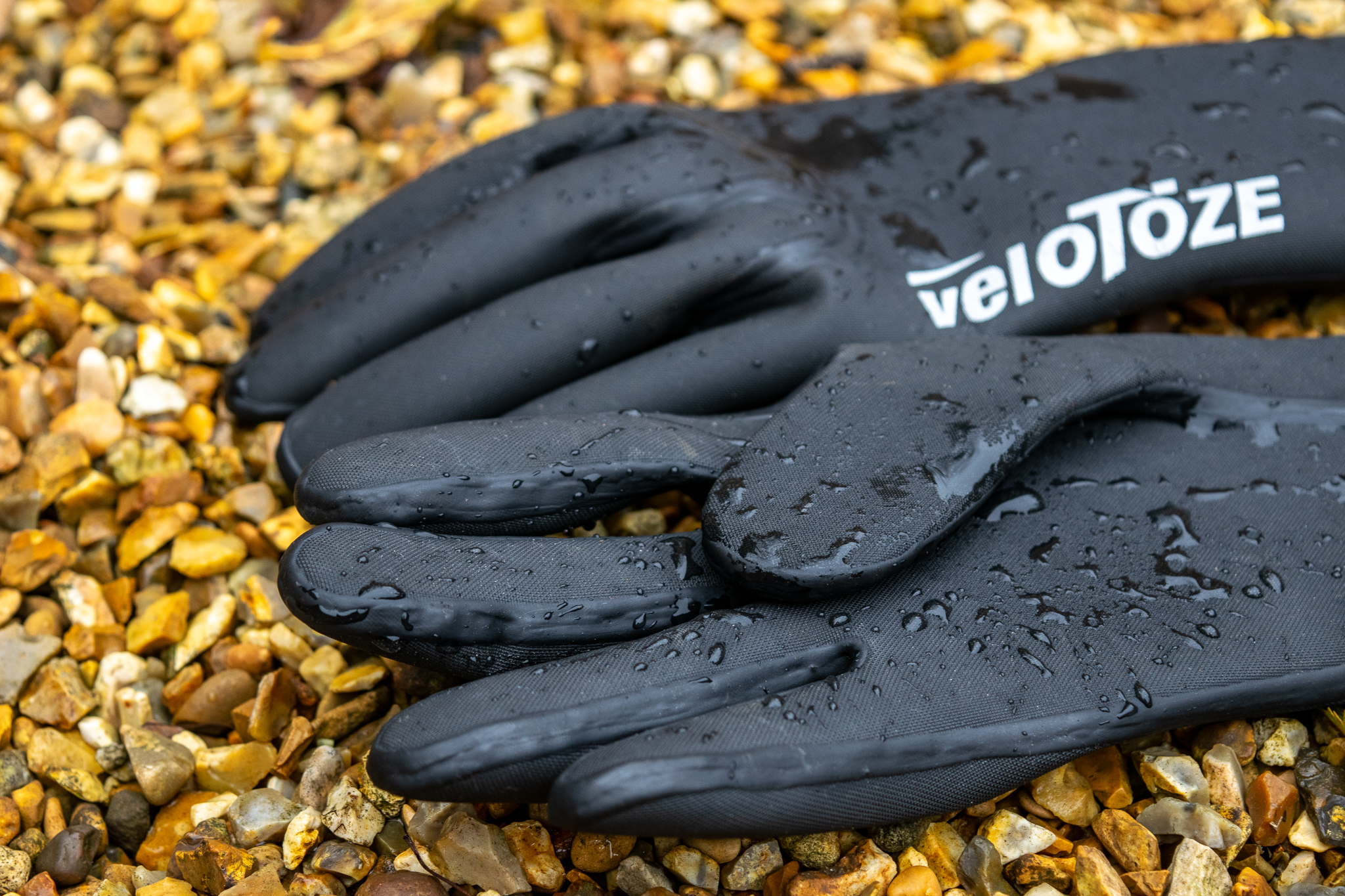 Velotoze neoprene gloves on some gravel with water droplets on them