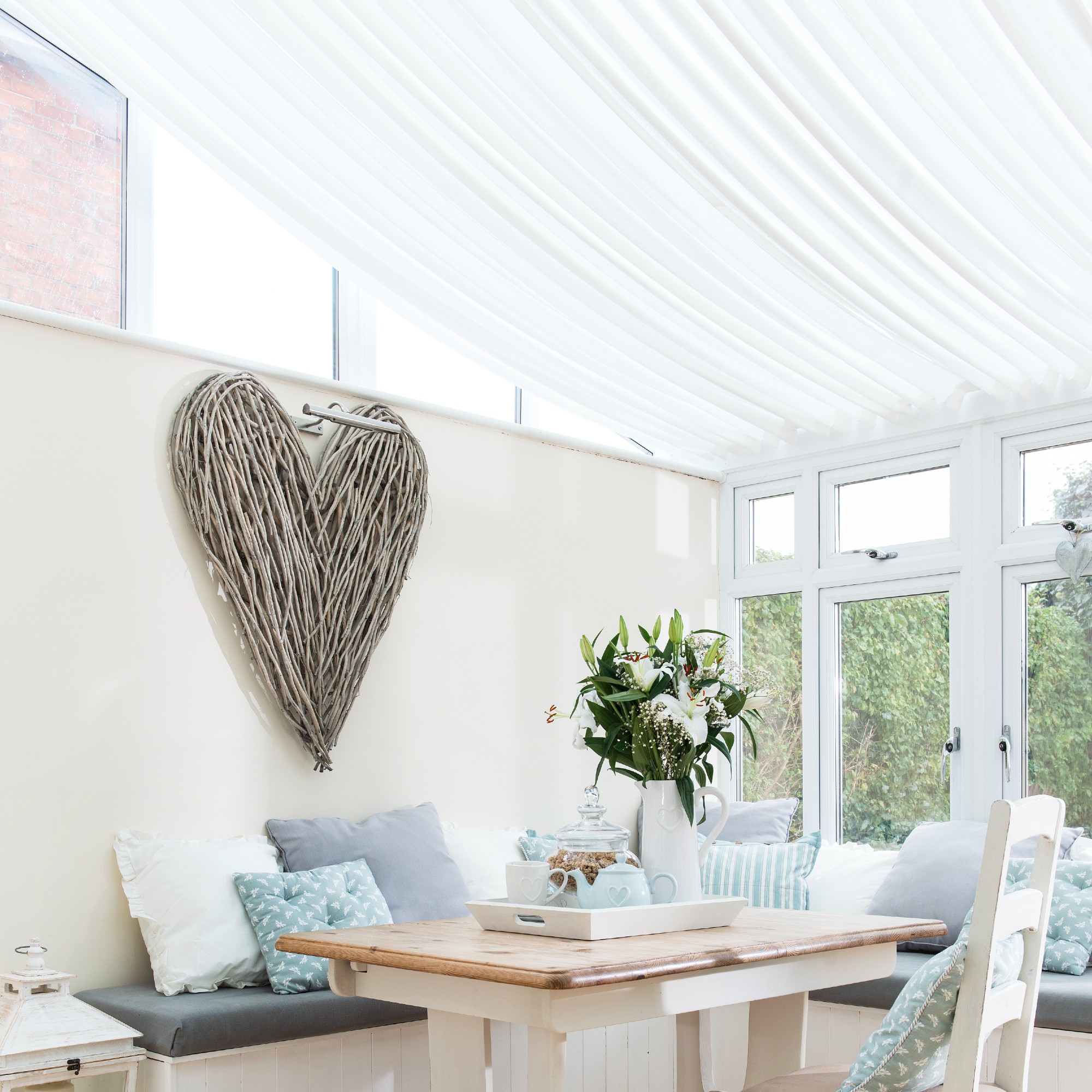 A bright conservatory with a dining area and a white sail blind