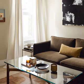 White bedroom with brown sofa, glass coffee table and abstract wall art
